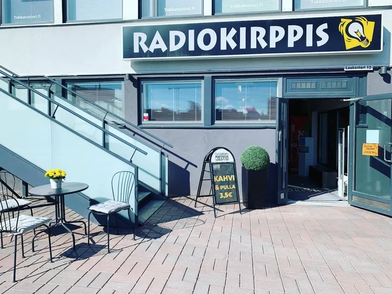 Radiokirppiksen sisäänkäynti Laukontori 12:ssa, kyltti, terassipöytä ja Kahvi & pulla -mainosteline